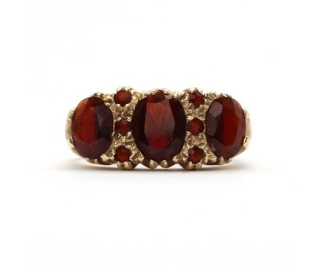 A 9ct gold three stone garnet ring,a row of three graduated oval mixed cut garnet, all claw set to belcher collets, with eigh