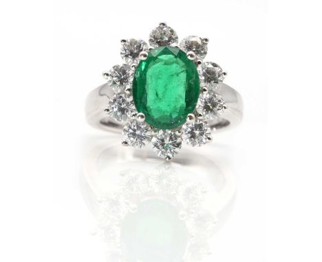 An 18ct white gold Zambian emerald and diamond oval cluster ring,with an oval mixed cut Zambian emerald, with a stated weight