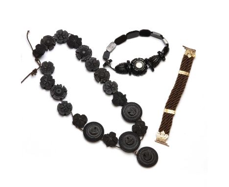 A carved jet bracelet,the central bead set with a compass, strung on elastic,10.83g,together with a woven hair bracelet, clas