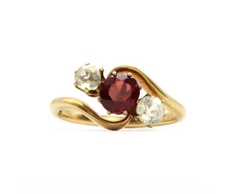 An Edwardian three stone garnet and white sapphire crossover ring,all claw set to plain collets. Marked 18ct, tested as appro