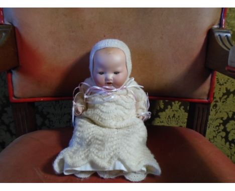 A composite bisque faced 1920's era Armand Marseille doll articulated limbs and blue sleepy eyes 12 inches dressed in knitted