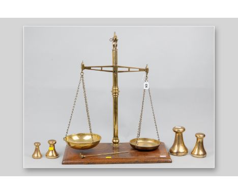A set of Victorian brass beam scales by W & T Avery on a moulded edge mahogany base along with four bell weights, measurement