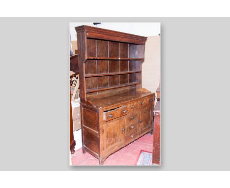 An antique oak and pine flat fronted Welsh dresser with three shelf Delft rack above, a good coloured four plank top, three f