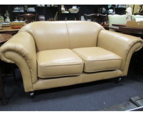 A two seater caramel coloured leather sofa, on turned legs and castors, 164cm wide  