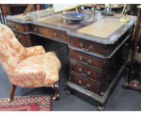 A Chippendale revival mahogany pedestal desk of recessed breakfront outline, with triple leather panel inset top, leaf carved