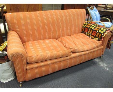 A Howard style sofa, upholstered in a pink canvas fabric with loose cushion seat and on tapering square legs and brass collar