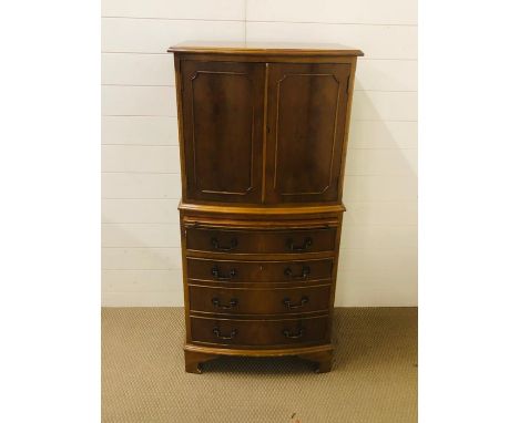 A bow fronted mahogany cabinet to include cupboard space, a drawer and a brush slide (H130cm D 40cm W60cm)