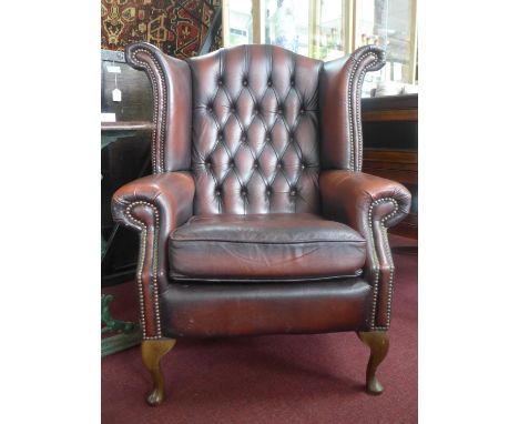 A 20th century stud bound button back leather wingback armchair, raised on cabriole legs 