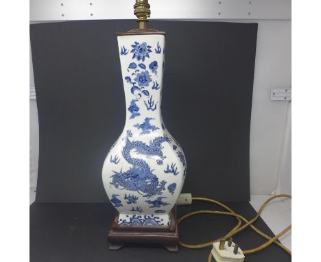 An early 20th century Chinese hand-painted blue and white lamp decorated with dragons on a fitted hardwood base, 48 x 15cm 