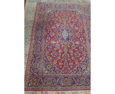 A Kashan carpet with central floral medallion surrounded by floral motifs, on a red ground, contained by floral borders, 207 
