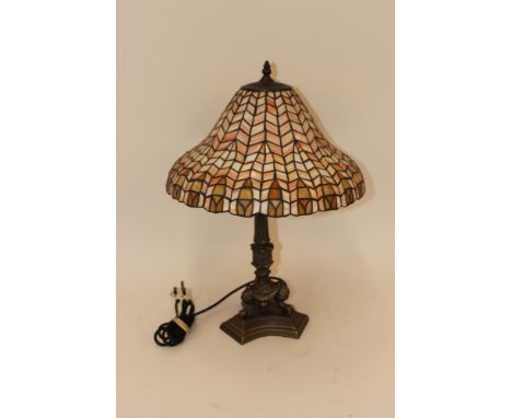 A gilded table lamp with foliate decoration, raised on claw and ball supports with a pink Tiffany style shade