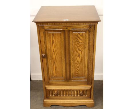 An Ercol side cabinet, enclosed by a single double fielded panel door with drawer below, 56cm wide