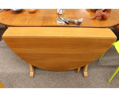 A light Ercol drop leaf dining table raised on shaped end supports, 127cm x 140cm fully extended