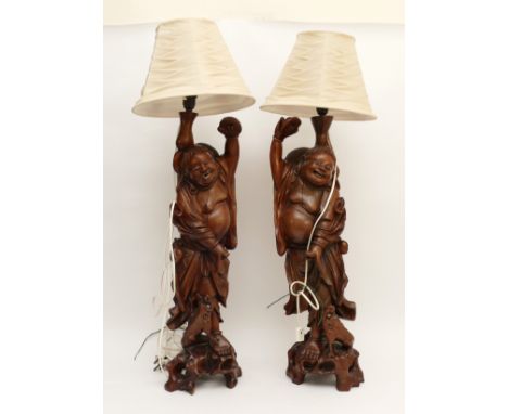 A Chinese pair of rootwood carved table lamps, depicting Budai, the laughing Buddha, with dogs at their feet, glass eyes, 67c