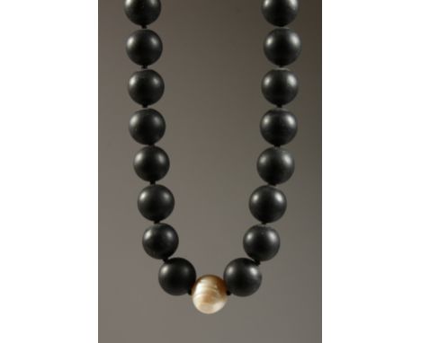 A HEAVY BLACK BEAD NECKLACE with a single pearl.