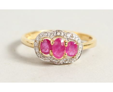 A 9CT GOLD OVAL THREE-STONE RUBY AND DIAMOND RING.