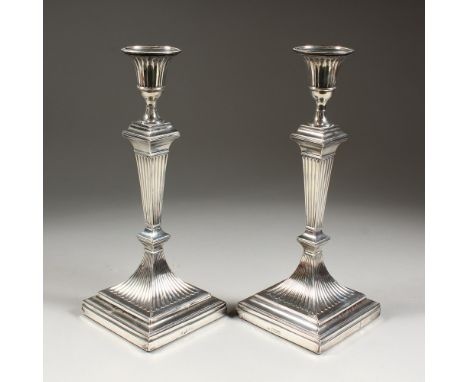 A PAIR OF EDWARD VII SILVER CANDLESTICK, on square loaded bases. London 1906.  Maker: The Hutton's.  12ins high.