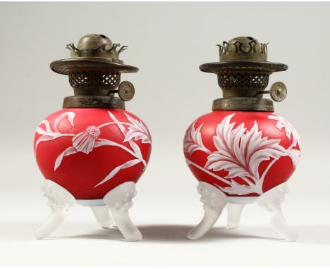 A PAIR OF RED AND WHITE CAMEO GLASS OIL LAMP BASES, with flowers, leaves and thistles. 7.5ins high.