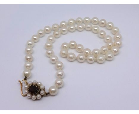 A single uniform row of culture pearls set with an oval garnet and pearl snap circa 1975, approx pearls 7mm, weight 29.3gms, 