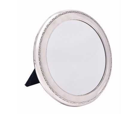 An Edwardian silver small circular dressing table mirror by Mappin & Webb, London 1907, plain with an embossed scroll border,