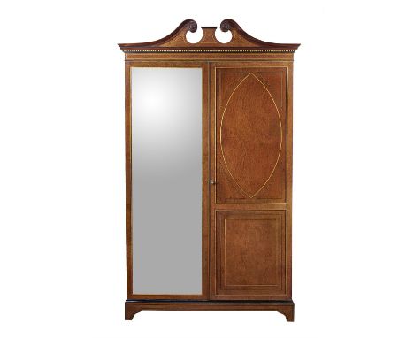 A amboyna wardrobe in George III style, late 19th century, the broken pediment above two doors, one with a mirror plate conce