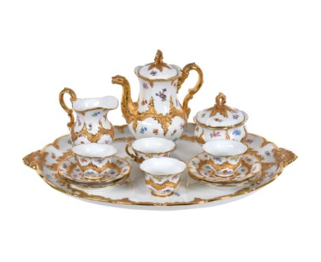 A Meissen cabaret coffee service, circa 1930, modelled in relief with gilt foliate C-scrollbaands and painted with scattered 