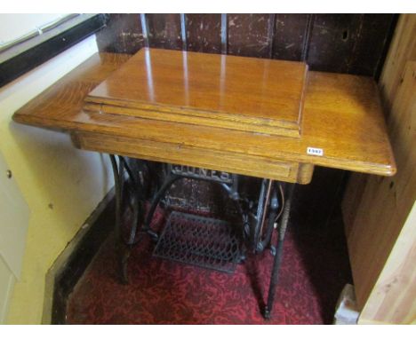 A vintage Jones treadle sewing machine with decorative cast iron base and oak top with hinged lid