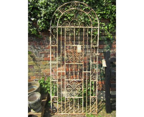 An iron work pedestrian side gate of arched form, with decorative scroll work panels and weathered cream painted finish, appr