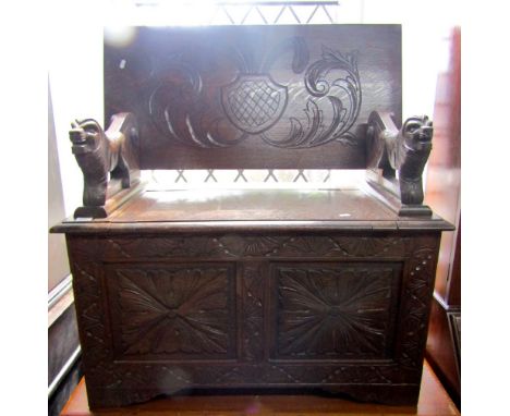 A Victorian oak monks bench, the lower section enclosed by carved and fielded panels with carved lion supports, tilting back 