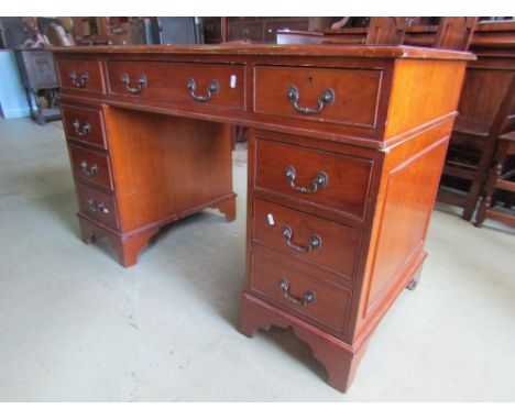 A reproduction Georgian style yew wood veneered knee hole twin pedestal writing desk, with inset leather top over an arrangem