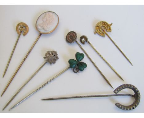 A collection of stick pins to include a yellow metal shell cameo example depicting a classical lady, a caved agate set clover