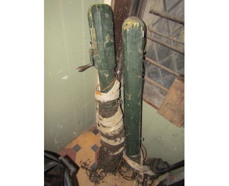 A pair of vintage wooden tennis posts with winding net mechanism and weathered green painted finish (complete with net)