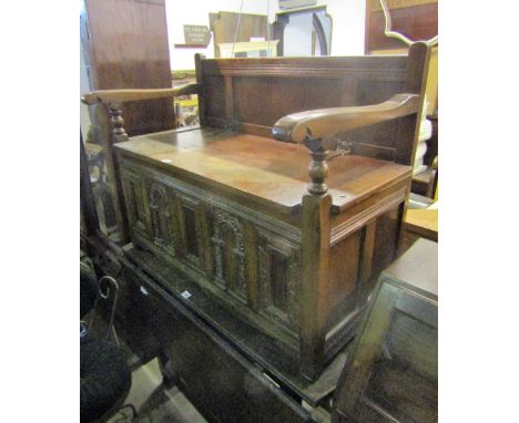 A reproduction oak hall bench with panelled back, open arms and box seat with hinged lid and arcaded panels, together with a 