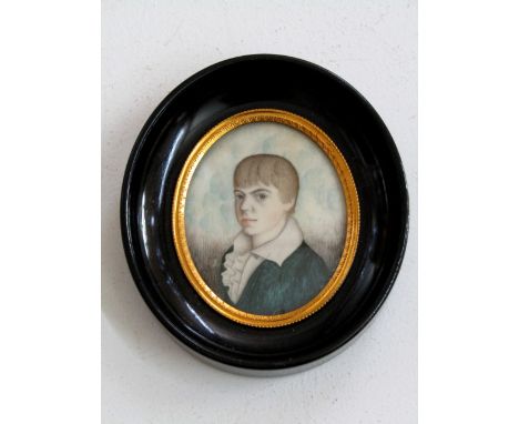 A 19th century portrait miniature of oval form - shoulder length portrait of a young boy in a green coat, 6 cm max, in black 