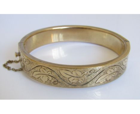 A 9ct hinged bangle with engraved scrolling vine decoration, 38g