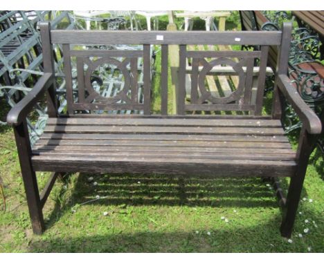 A stained hardwood two seat garden bench with slatted seat and circular twin ring panelled back
