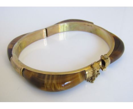 A 14k tigers eye bangle, the hinged mount engraved with foliate decoration, 24.5g (af)