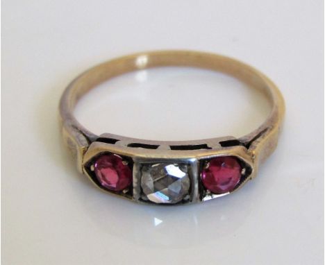 A yellow metal ring set with a rose cut diamond flanked by two rubies to chevron shoulders, size L, 2g