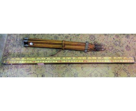 A vintage beech and cast metal theodolite stand, with leather straps, together with a further measuring stick (2)