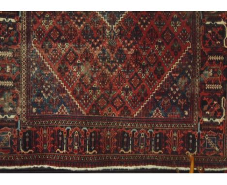 Persian carpet decorated with geometric floral patterns around a blue medallion upon a red ground, 320 x 220 cm 