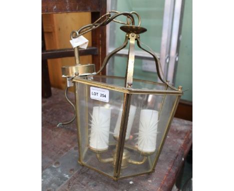Brass and glass porch light with triple candle bulb.