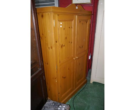 A contemporary pine two door wardrobe, cupid's bow pediment, panelled doors, button handles, plinth base. 168cm high x 100cm 