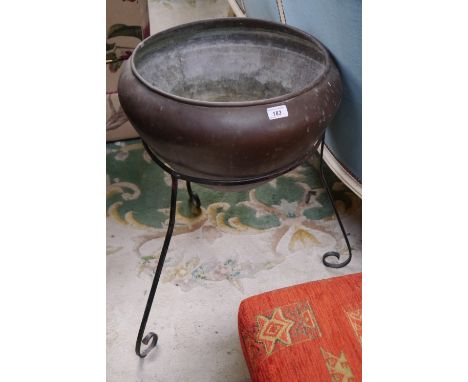 A copper planter with iron tripod stand.
