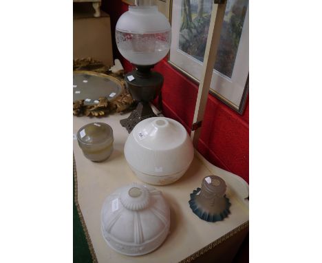 A cast metal oil lamp base with green glass section;  an ovoid frosted glass oil lamp shade, decorated with floral motifs;  a