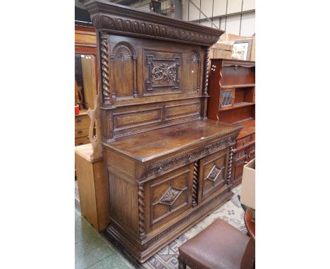 An oak panel back sideboard, outswept cornice, dentil worked frieze with carved foliage supported by barley twist columns, th
