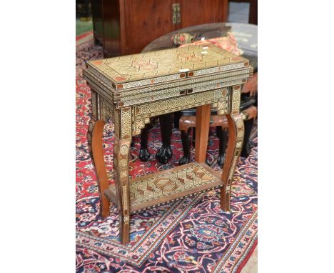 An Islamic gaming table, inlaid with mother of pearl, stone and wood, fold over swivel top enclosing baize playing area, back