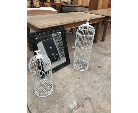 TWO WHITE BIRD CAGES OF DIFFERENT SIZES AND A DECORATIVE FRAMED MIRROR 