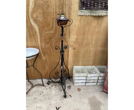A DECORATIVE BRASS AND COPPER OIL LAMP ON A TALL DECORATIVE BLACK CAST IRON METAL STAND (H:137CM) 