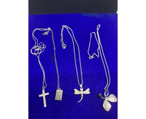 FOUR SILVER NECKLACES WITH PENDANTS TO INCLUDE A FLOWER, DRAGON FLY, LOCKET AND CROSS MARKED 925 /STERLING 