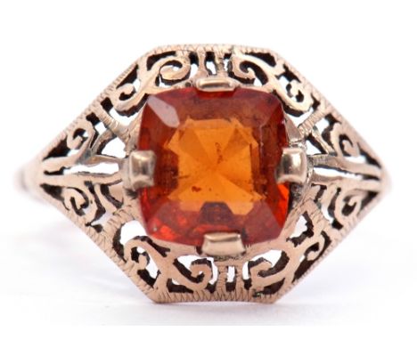 Yellow metal citrine set ring, the pierced scroll mount cardinal set with a square faceted citrine, (unmarked), size K/L (a/f